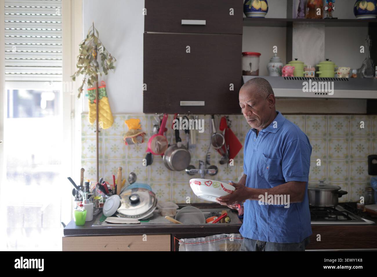 Senior man doing chores in a sunlit kitchen Stock Photo