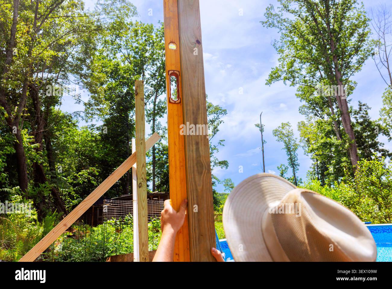 Frame worker works on erecting wooden post while using level tool under construction location Stock Photo