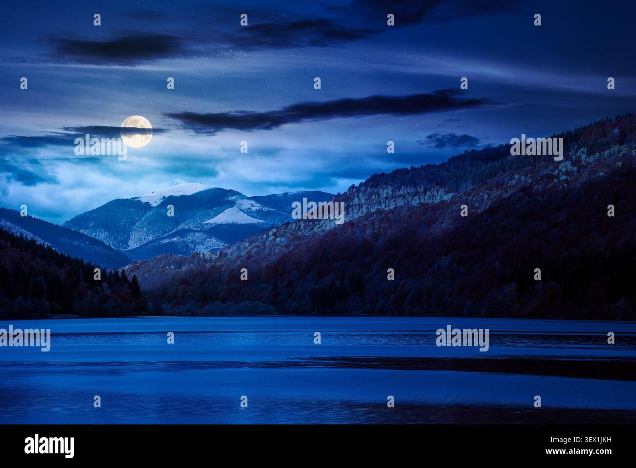 landscape with lake in autumn at night. full moon over scenic view of forest reflection on the lake surface. rika river water reserve. transcarpathia Stock Photo