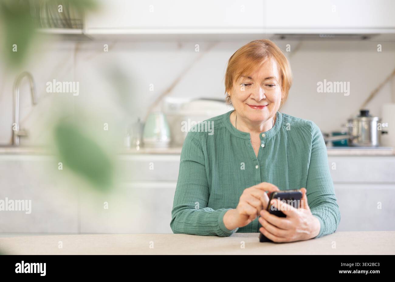 Smiling older woman sending messages using smartphone with someone on her phone Stock Photo