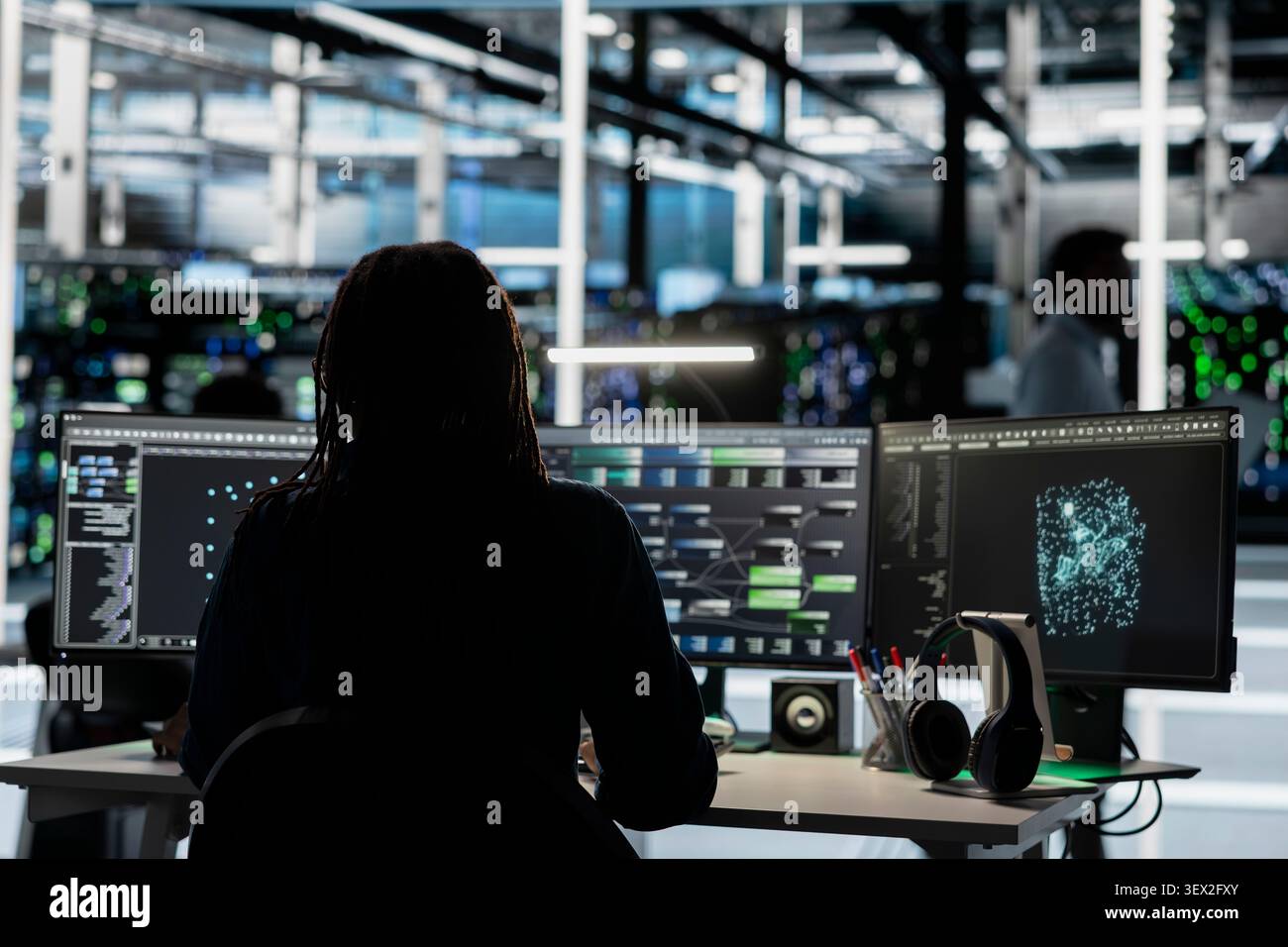 Data center engineer uses a desktop computer in a data center to manage AI visualization and optimize server infrastructure. Stock Photo