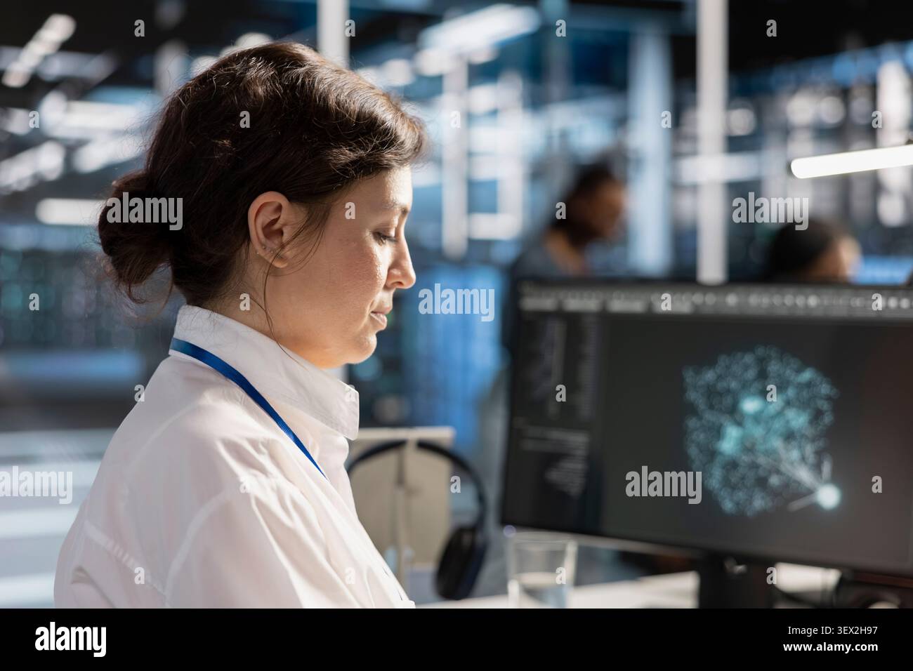 Computer scientist reviews performance analytics on a desktop computer in a data center to optimize storage systems and resource use. Stock Photo
