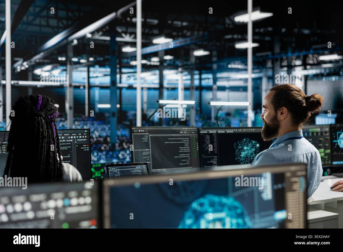 Computer scientist uses a desktop computer in a data center to manage AI systems and optimize server infrastructure. Stock Photo