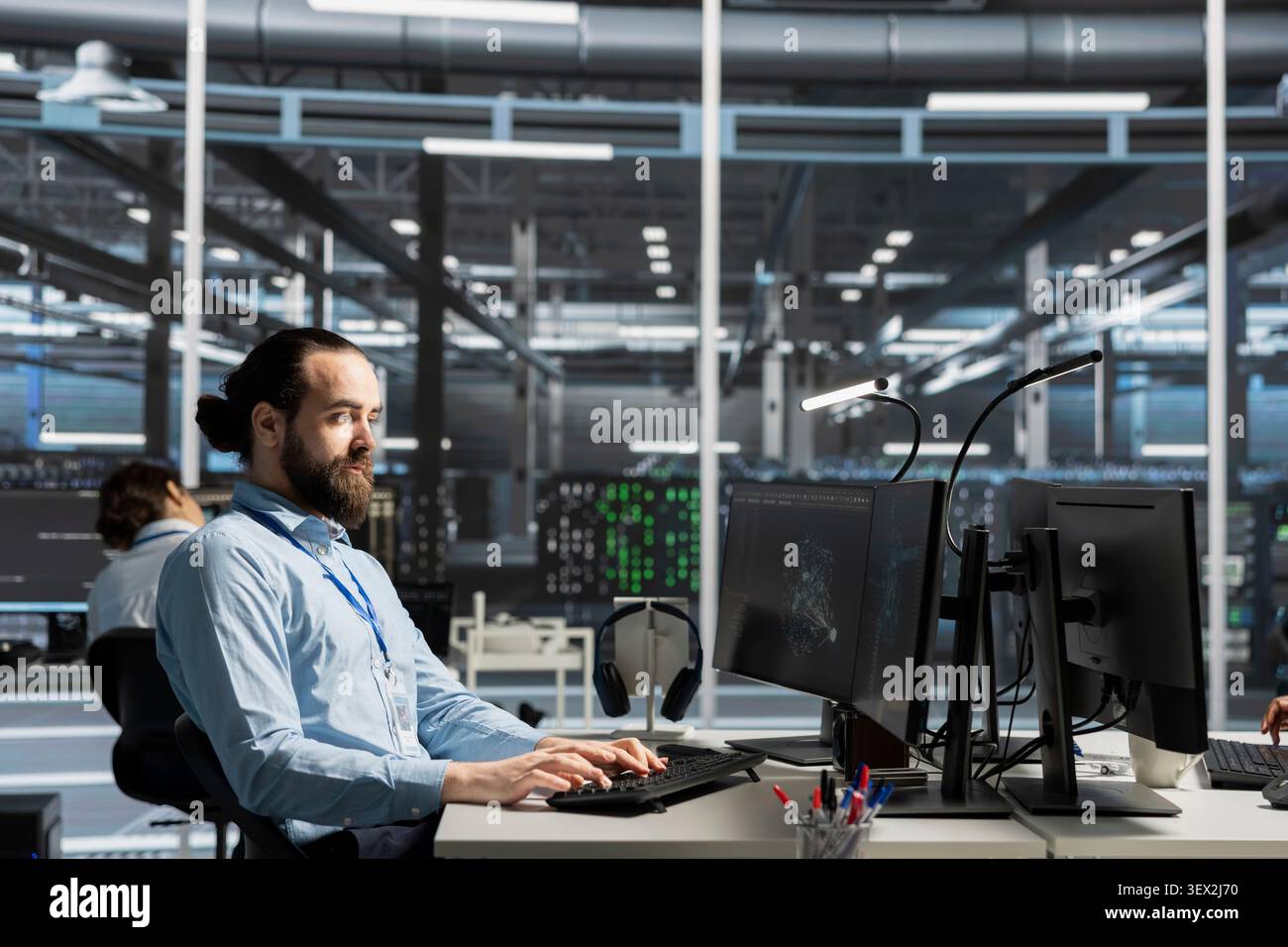 System administrator uses a computer to run diagnostics, update servers and check infrastructure performance. Stock Photo