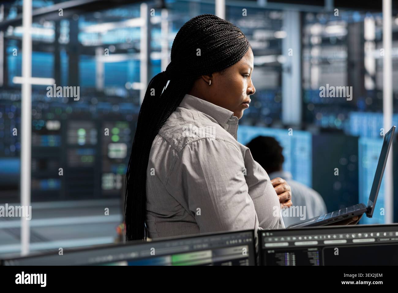 System administrator uses a laptop to run diagnostics, update servers and check infrastructure performance. Stock Photo