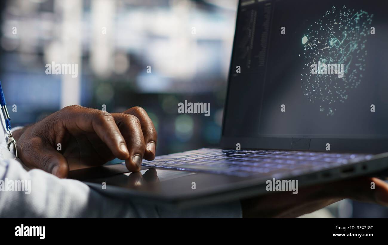 Data center technician monitors AI systems and machine learning workloads on a laptop inside a high-tech server facility. Stock Photo