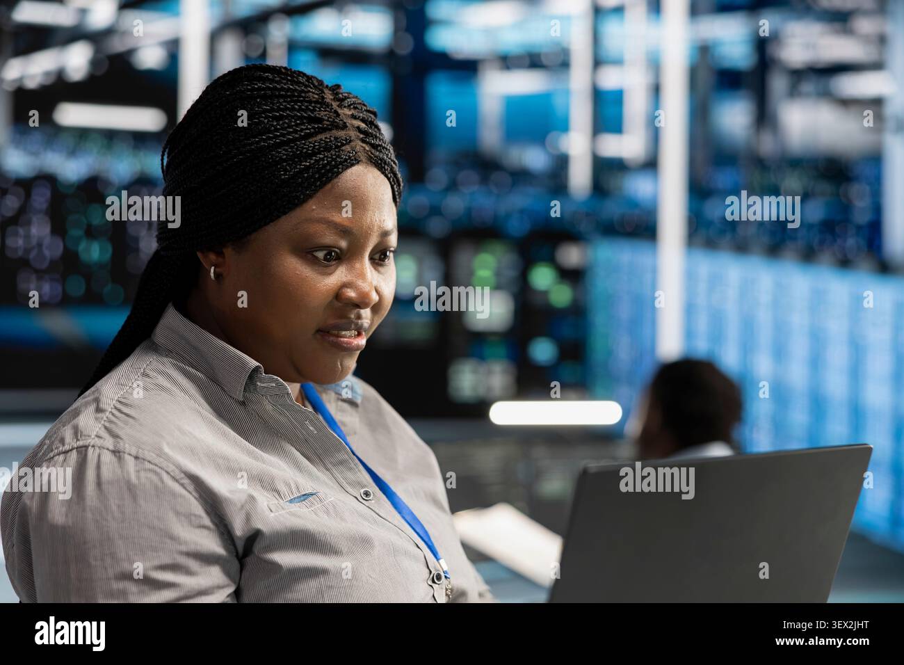 Stressed engineer panics over errors while overseeing data center machines, struggling with glitches during server rig maintenance. Stock Photo