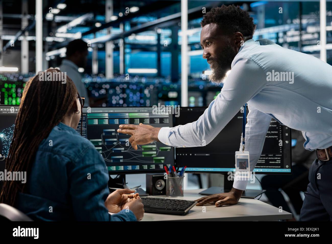 African American computer scientists set up machine learning node trees, training neural networks to improve server farm operations. Stock Photo