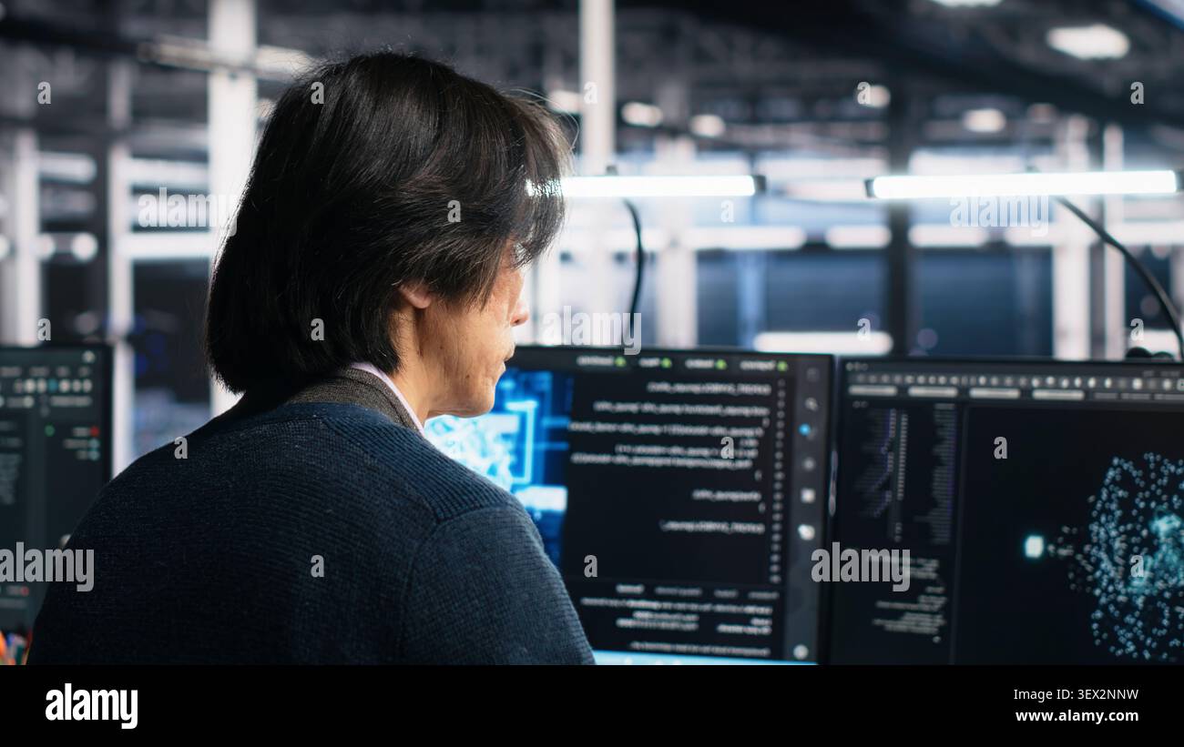 Technician programs on a computer workstation in a data center with generative AI assistance. Stock Photo