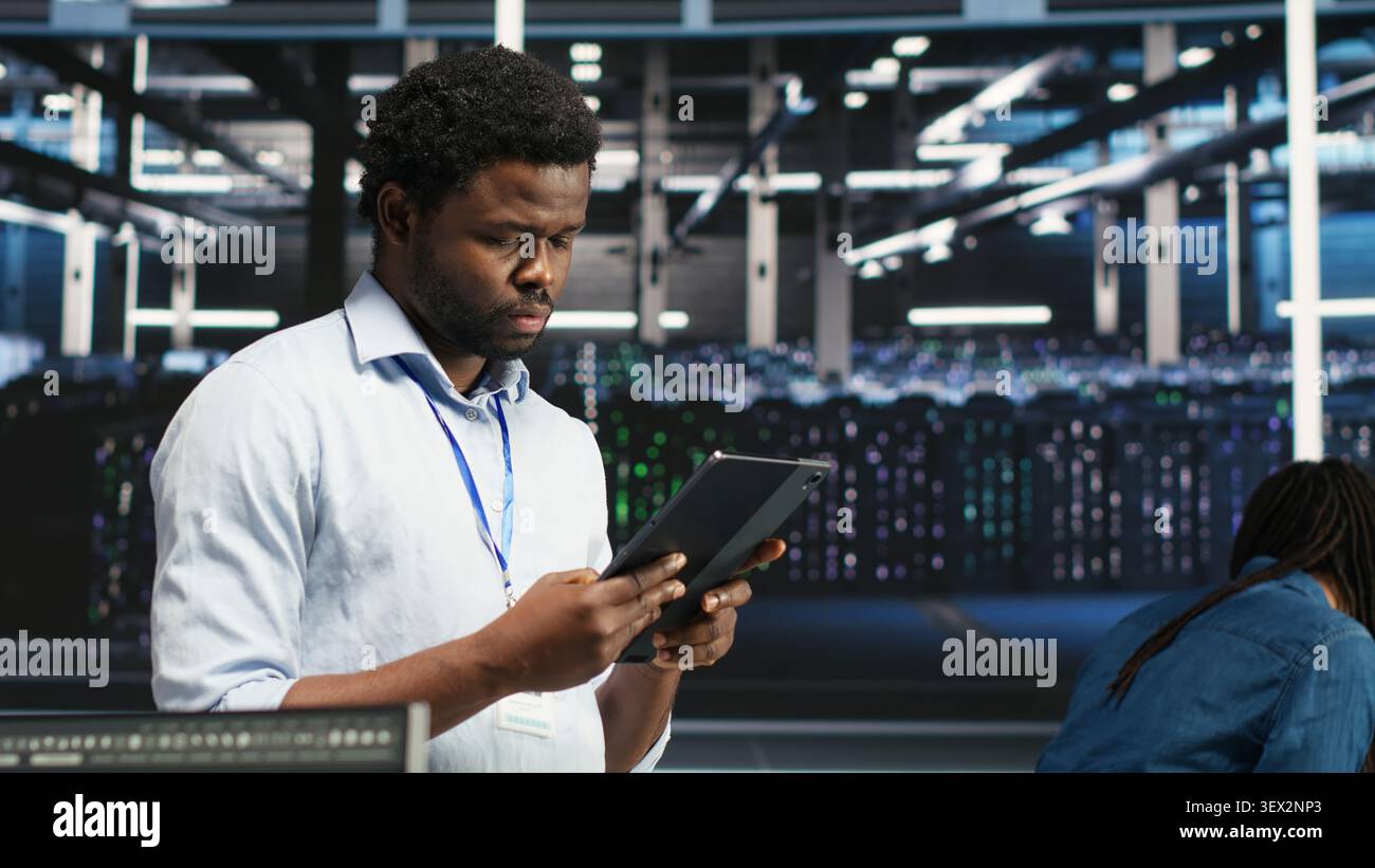 Data center technician uses a tablet with node tree programming to optimize resource allocation and analytics. Stock Photo