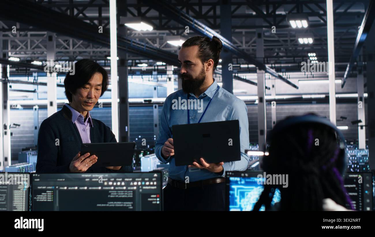 IT colleagues collaborate in a data center while reviewing AI diagnostics and infrastructure performance. Stock Photo