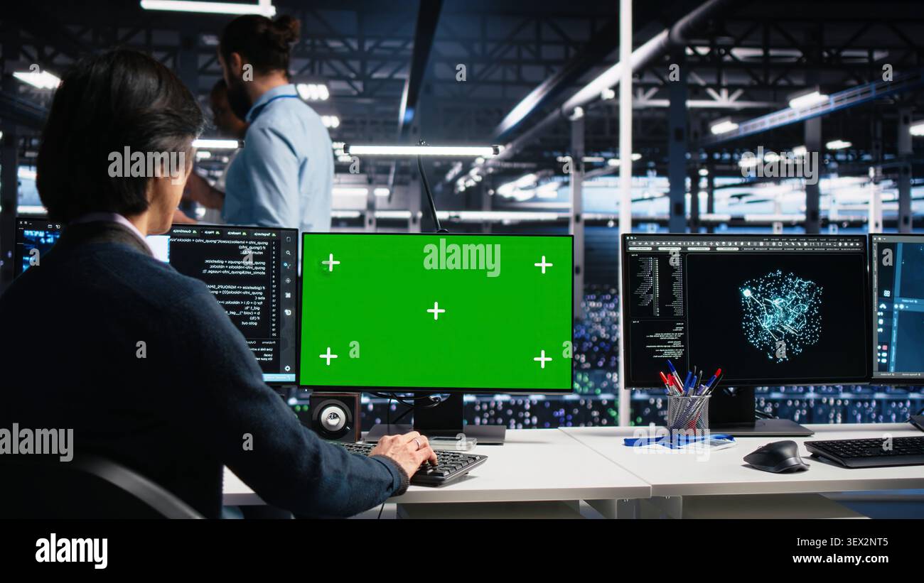 Technician programs on a green screen computer in a data center with generative AI assistance. Stock Photo