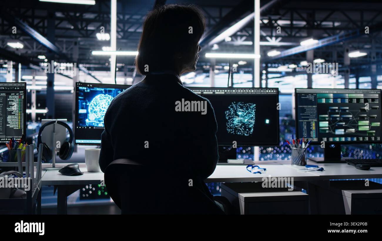 Computing facility software developer working with computer to track neural network AI large language model visualization with in high tech facility working with computer to oversee servers. Stock Photo