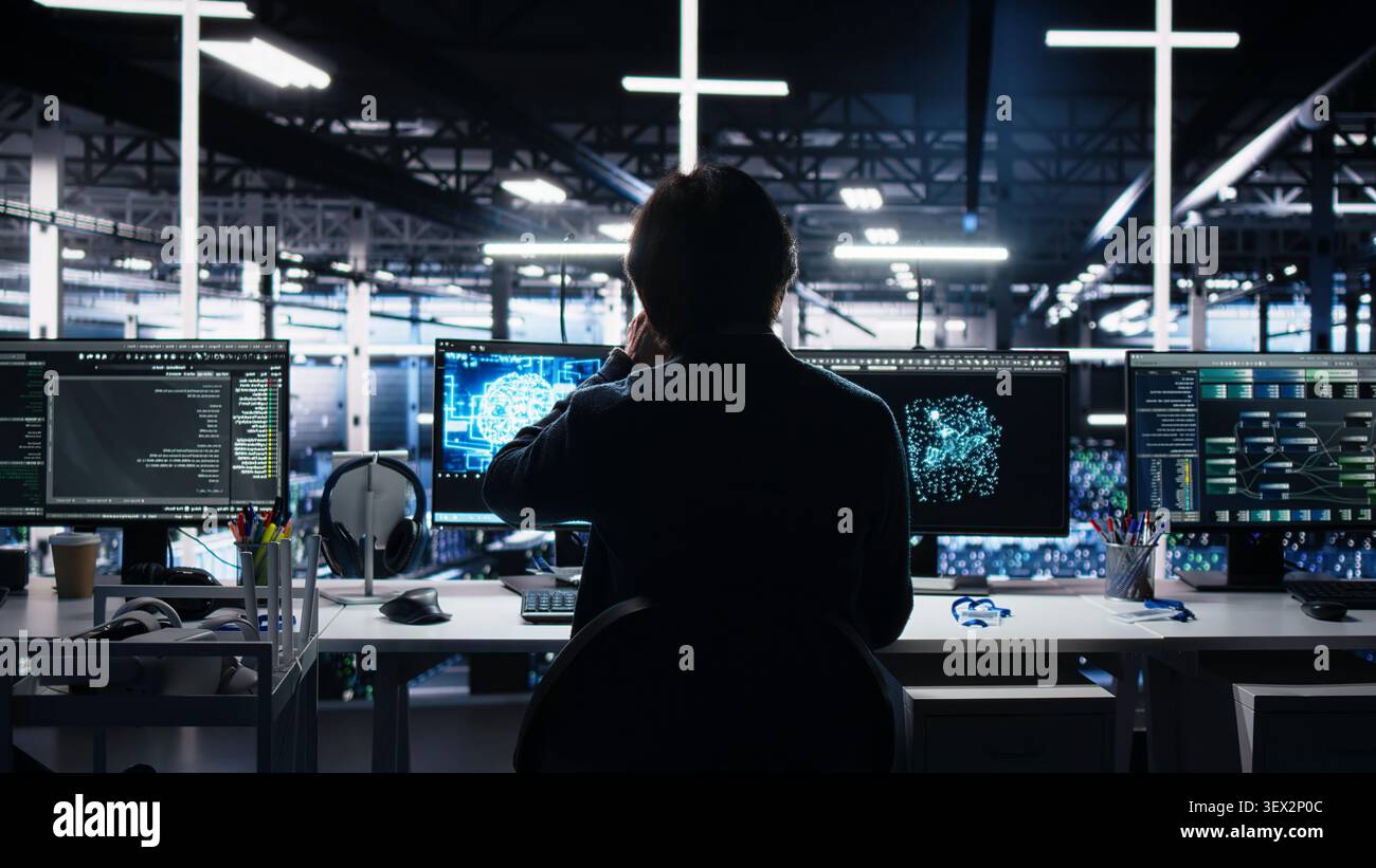 Programmer programs on a computer workstation in a server room with generative AI assistance. Stock Photo