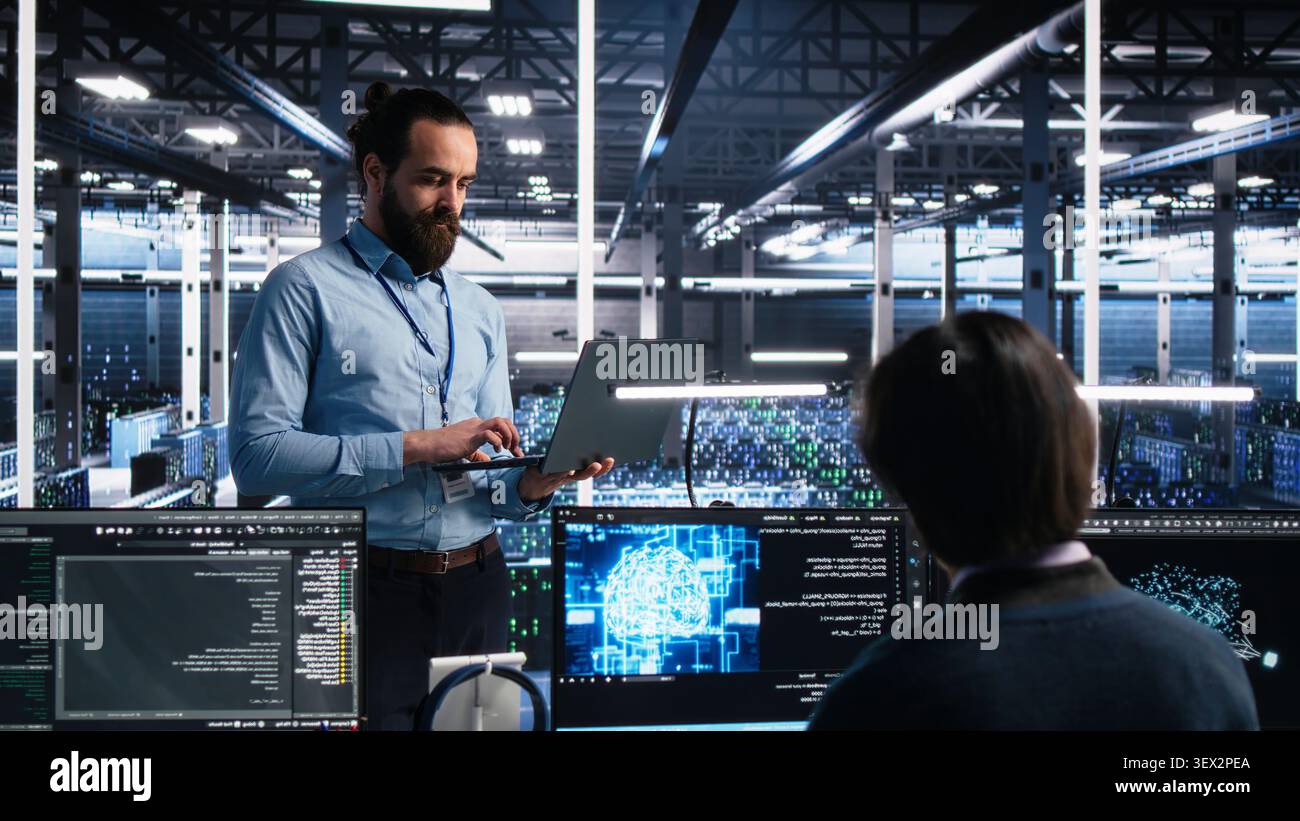 Computing facility IT technician working with notebook to track neural network AI large language model visualization with in high tech facility working with notebook to oversee servers powering. Stock Photo