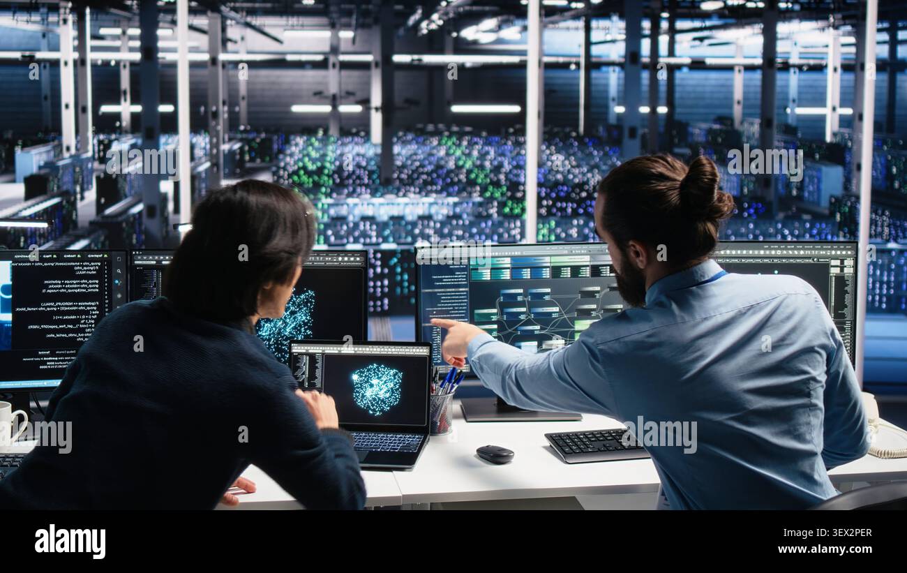 Data infrastructure center admins brainstorming, working on neural network software development, while IT staff members collaborating, implementing machine learning technology working with computer. Stock Photo