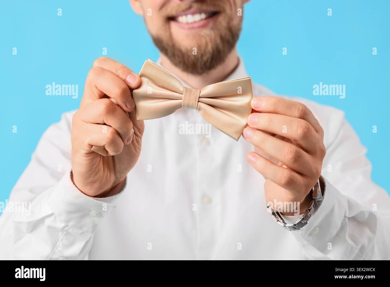 Man holding beige bow tie smiling Stock Photo