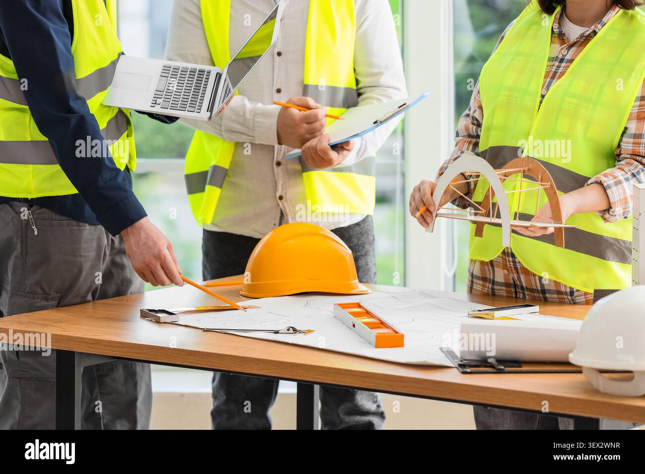 Engineers discussing bridge model and blueprints Stock Photo