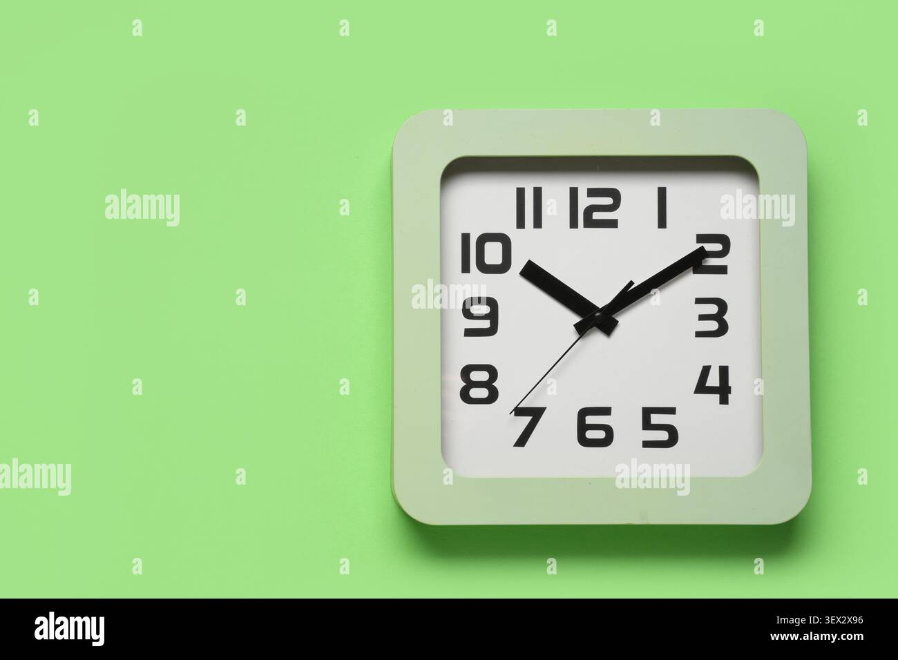 Square wall clock on green background Stock Photo