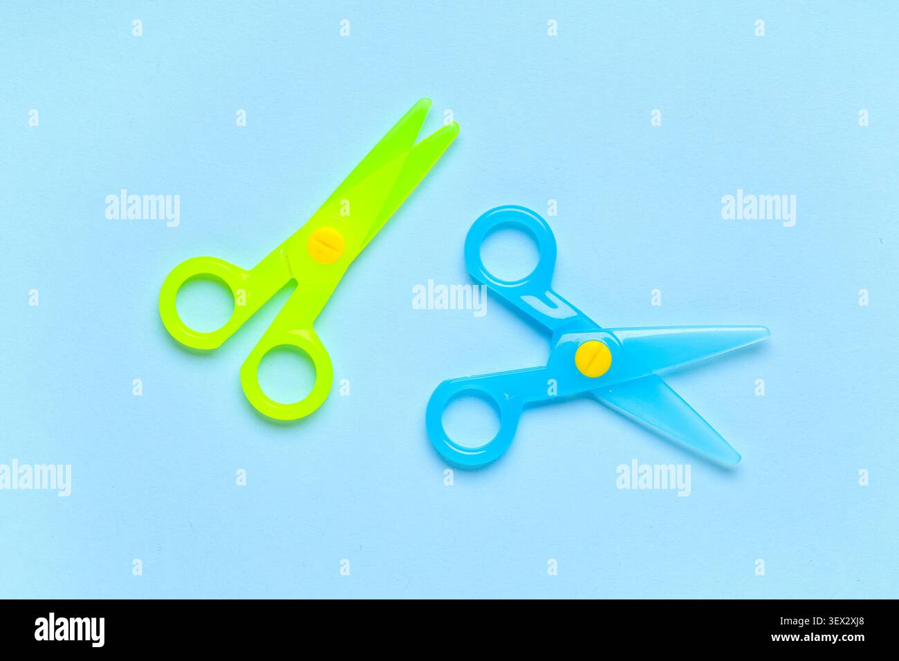 Blue and green plastic scissors on blue background Stock Photo