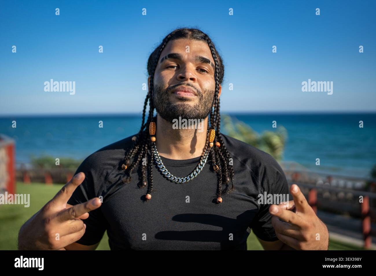 Young man showing peace sign by ocean Stock Photo