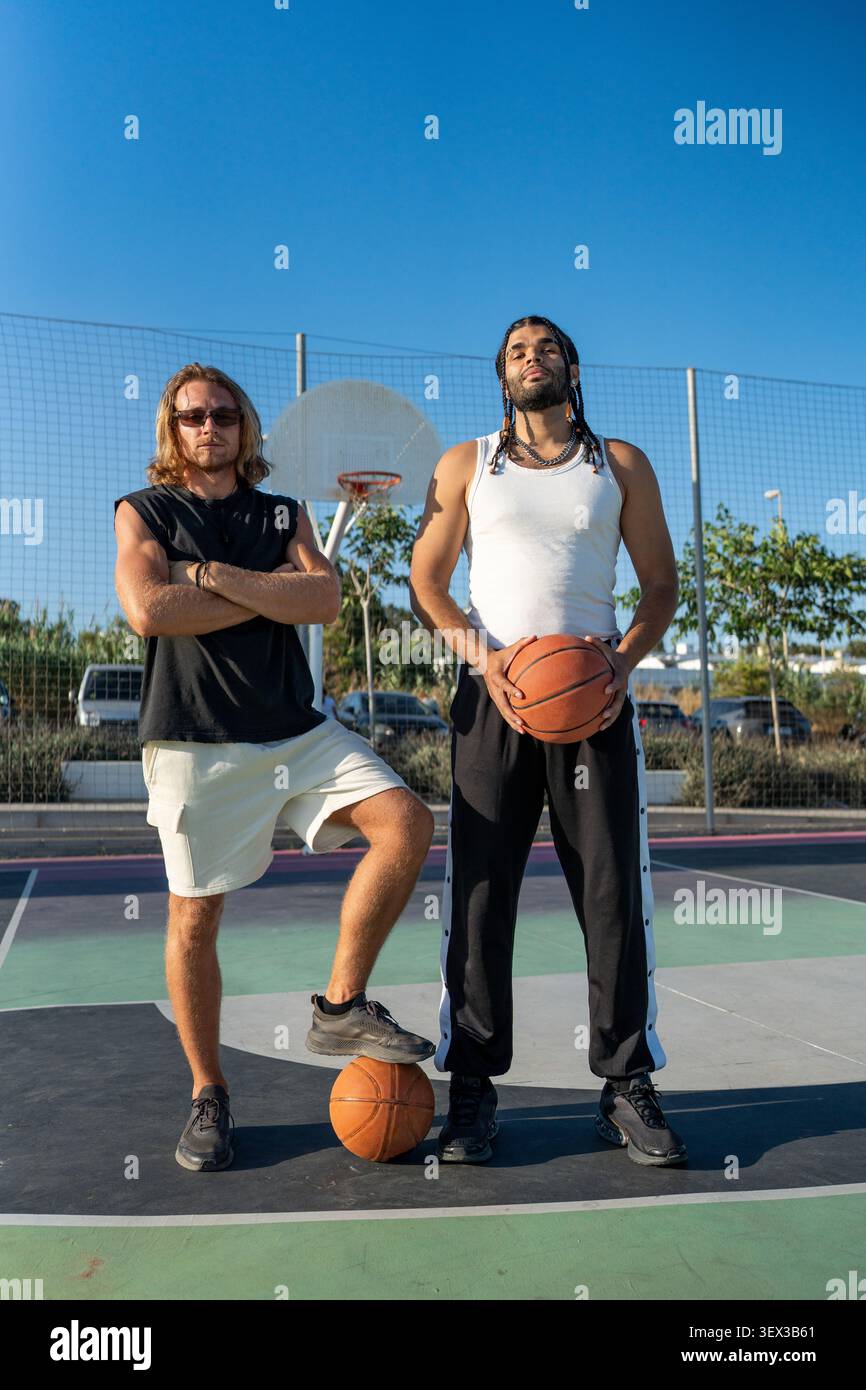 Diverse men posing on outdoor basketball court Stock Photo