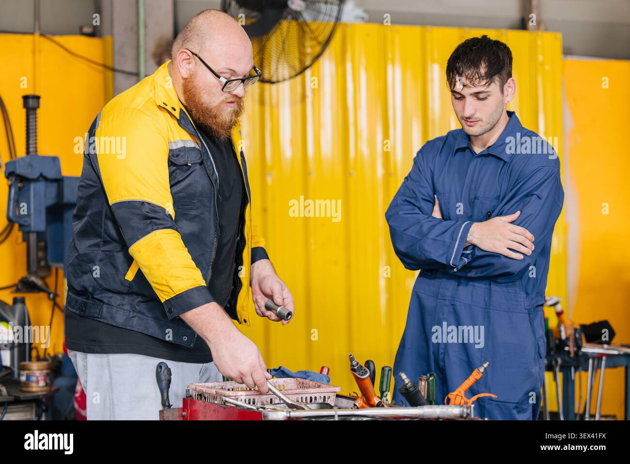 Mechanic worker in garage auto service center working service maintenance modern car with professional skill and safety uniform. Stock Photo