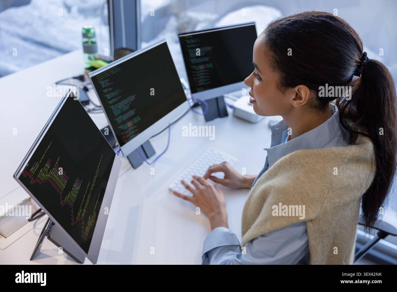 Woman engineer programming on multiple screens in office Stock Photo