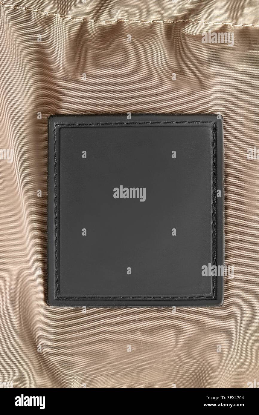 Blank black rubber patch stitched on beige waterproof fabric background Stock Photo