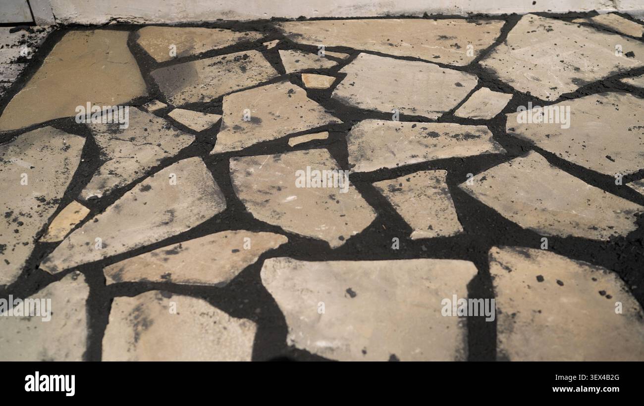 Broken stone pavement with dark mortar and weathered texture Stock Photo