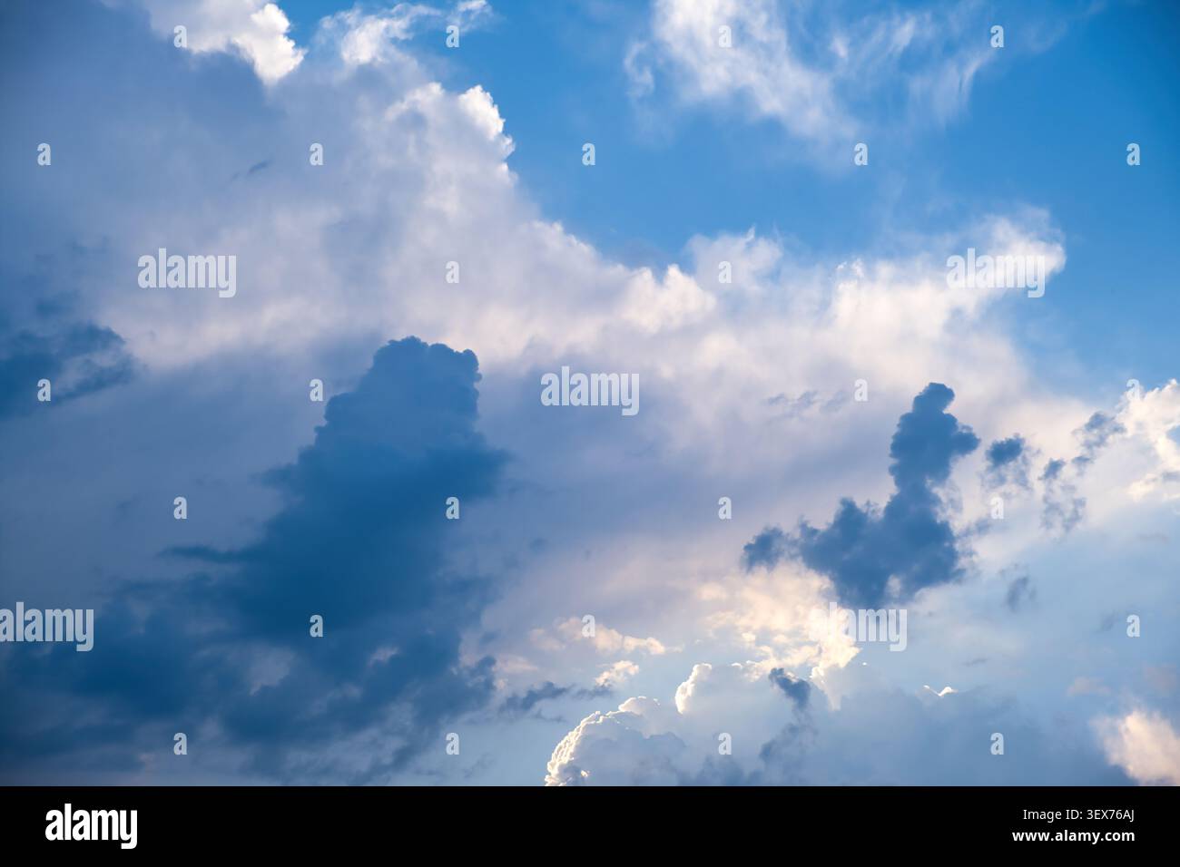 Dramatic sky with dark storm- and thunder clouds and bright sunlight breaking through Stock Photo