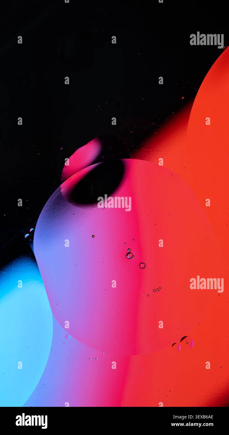 Oil drops creating an abstract pattern with gradients of red, blue, and purple color Stock Photo