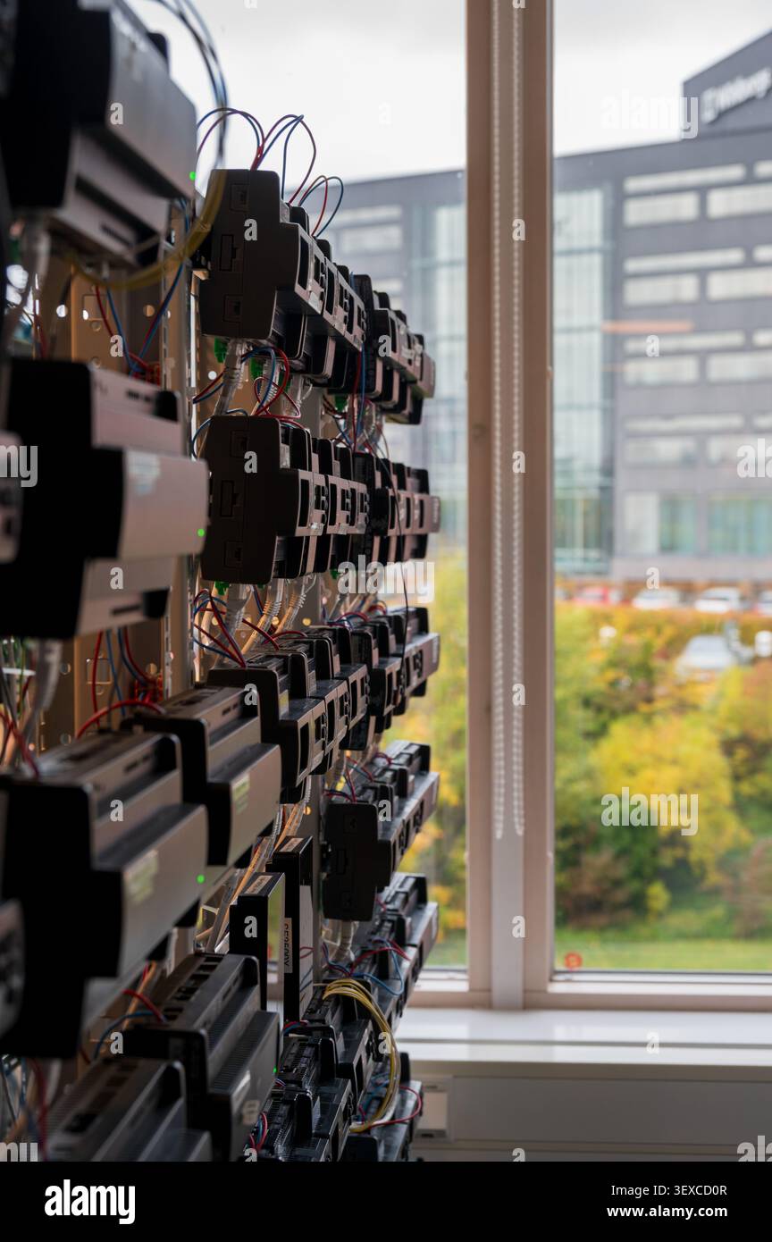 Server rack and network equipment mounted along a window in a tech facility Stock Photo