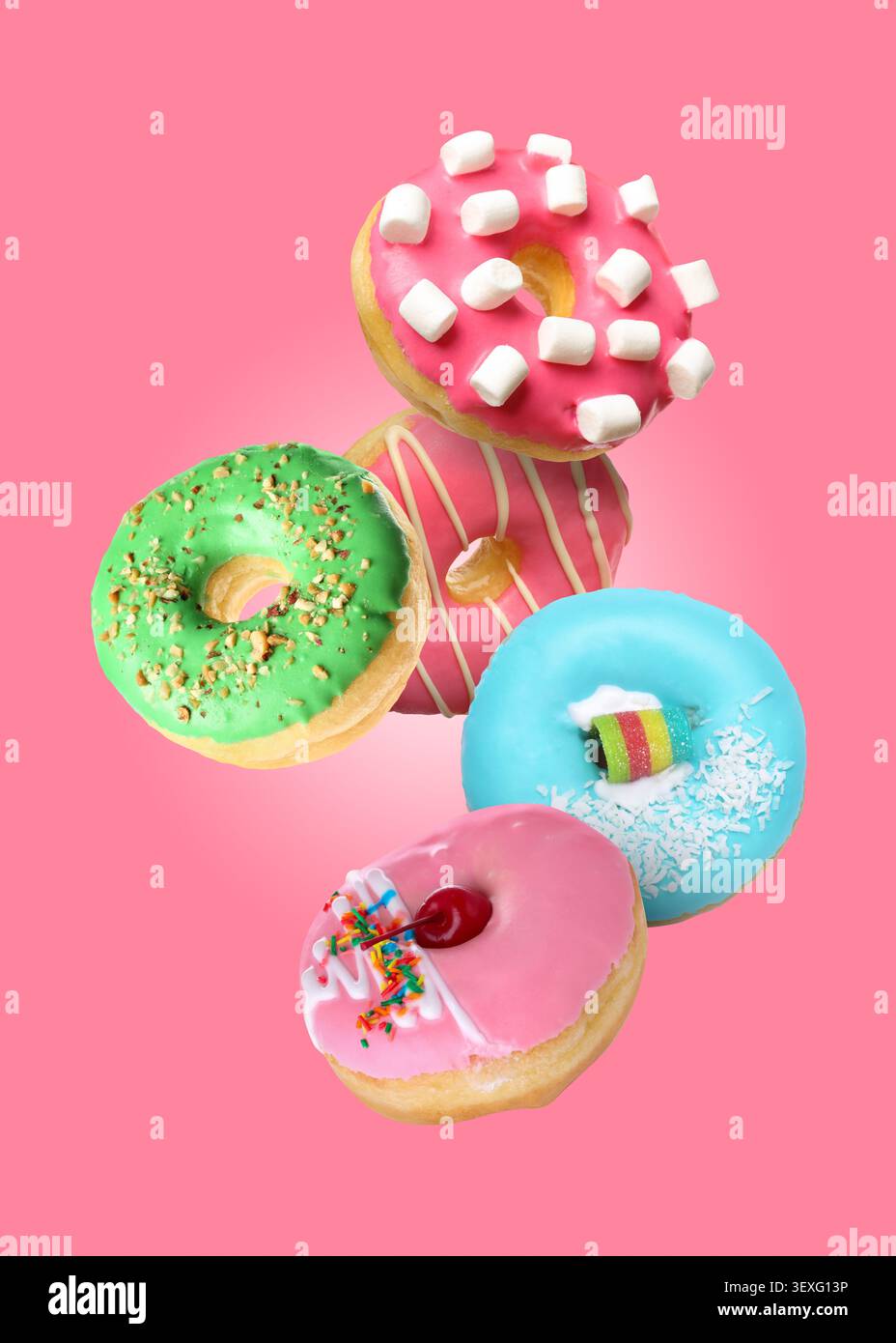 Yummy donuts covered with icing falling on pink background Stock Photo