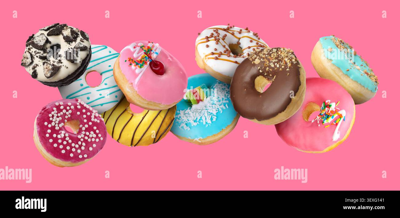 Sweet donuts covered with icing falling on pink background Stock Photo