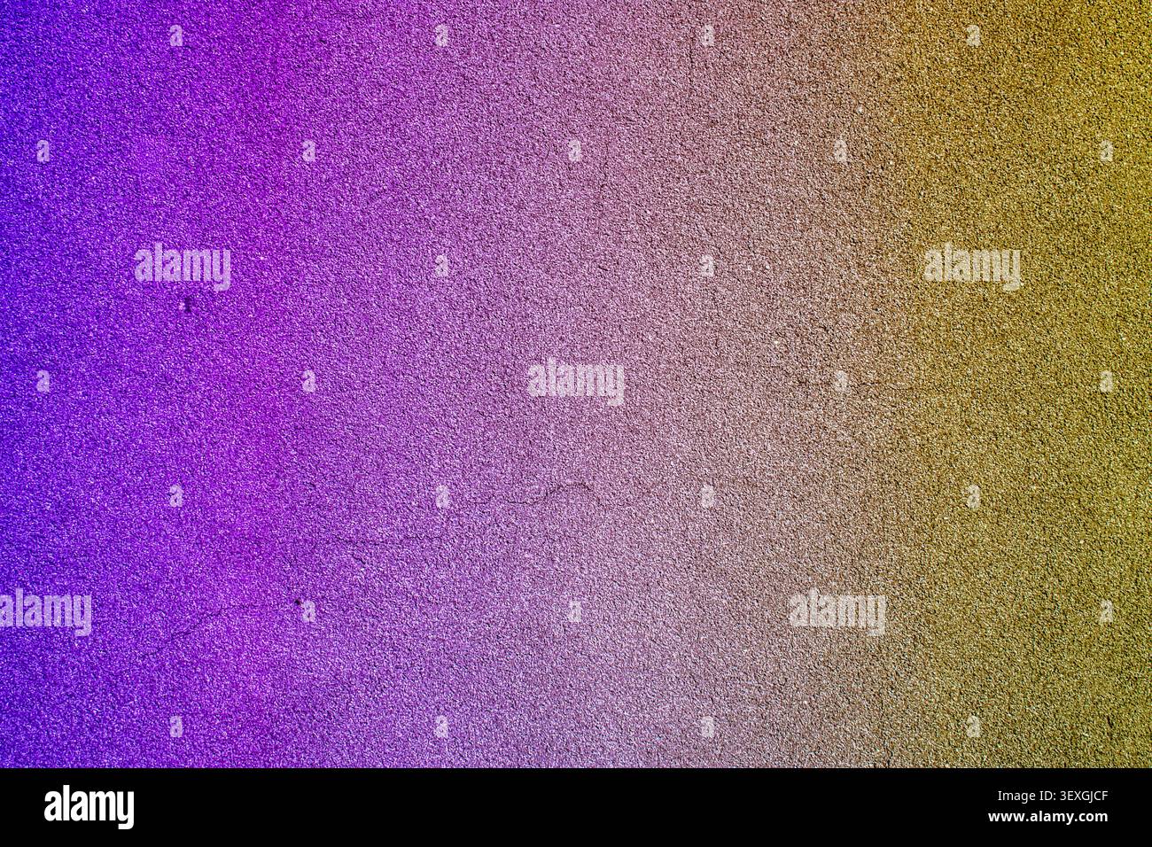 High-resolution texture showcasing a smooth color gradient transitioning from deep purple and violet to a shimmering golden yellow. The grainy, sparkl Stock Photo