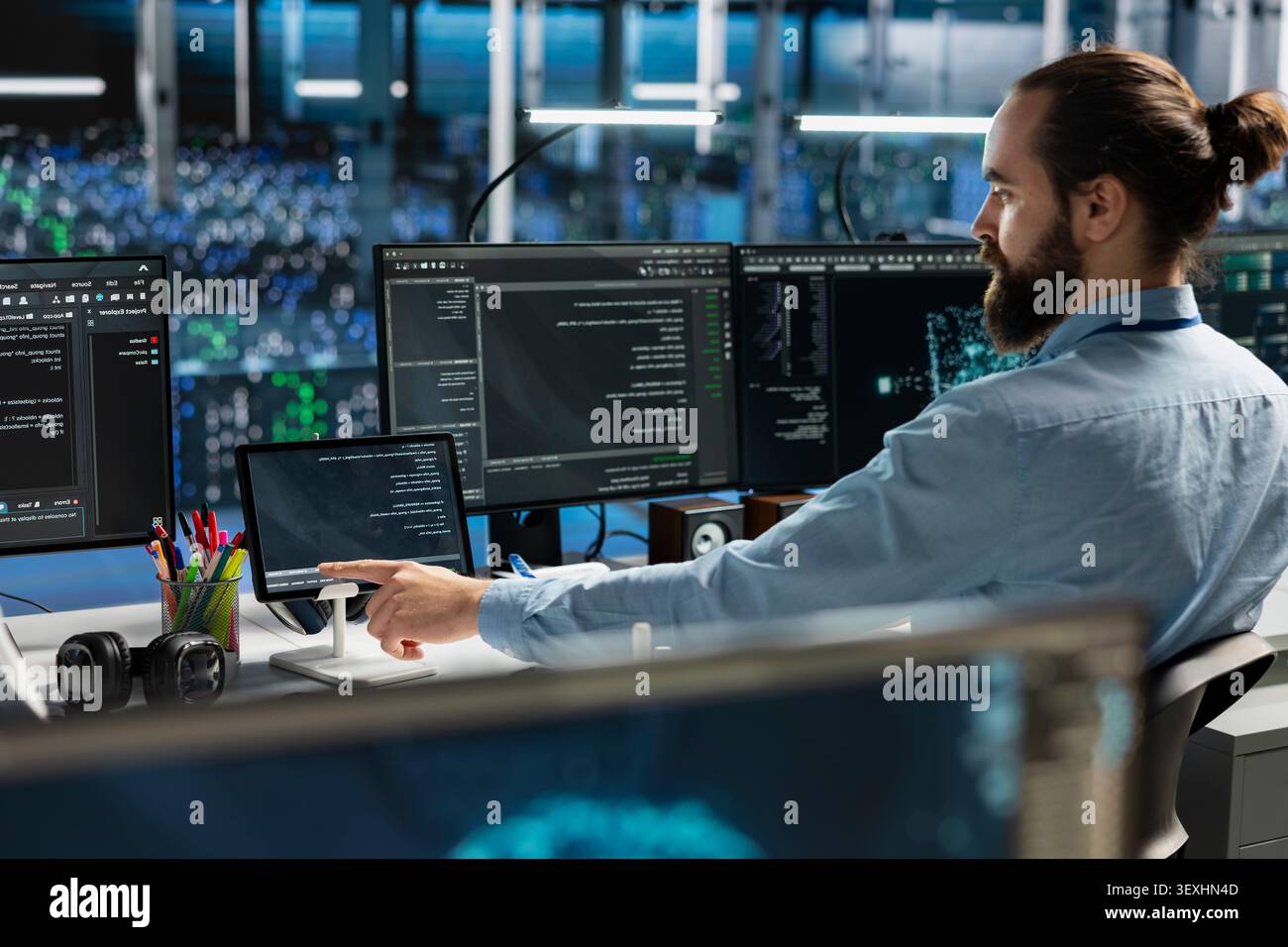 System administrator uses a digital tablet in a data center to deploy software updates, configure hardware, and support reliable operations. Stock Photo