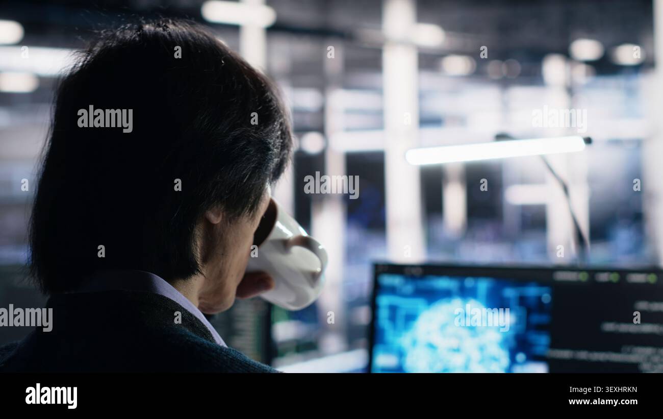 Software developer programs on a computer workstation in a server farm with generative AI assistance. Stock Photo