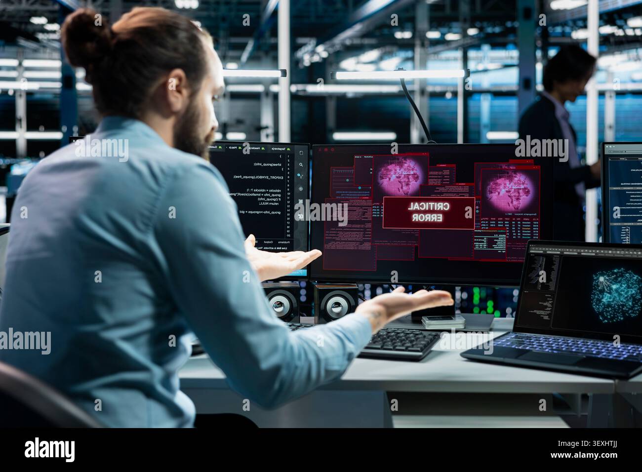 Computer scientist works with a computer workstation in a server farm to support artificial intelligence systems. Stock Photo