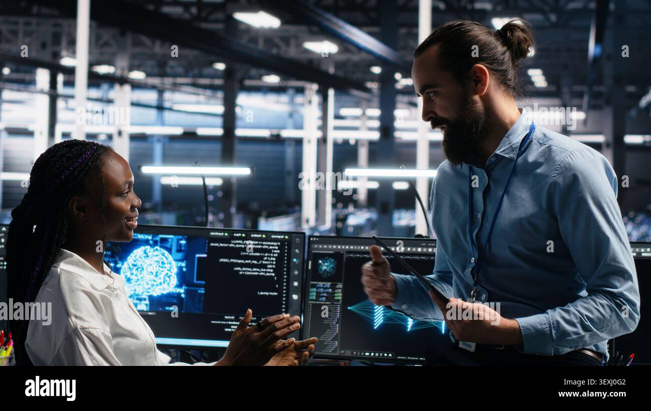 Woman programs on a computer workstation in a data center with generative AI assistance. Stock Photo