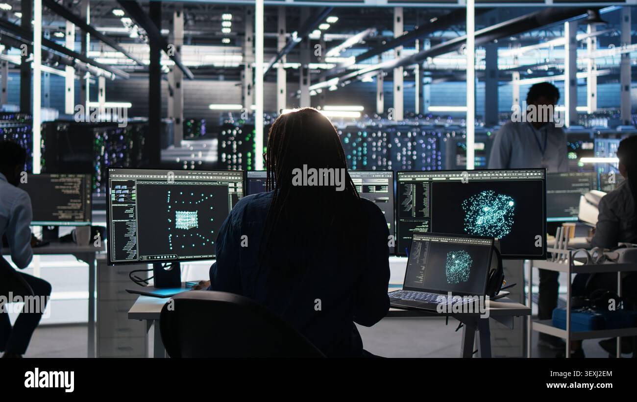 Data infrastructure center software programmer arriving at the office operates visual programming workflow to detect equipment operational performance issues. Stock Photo