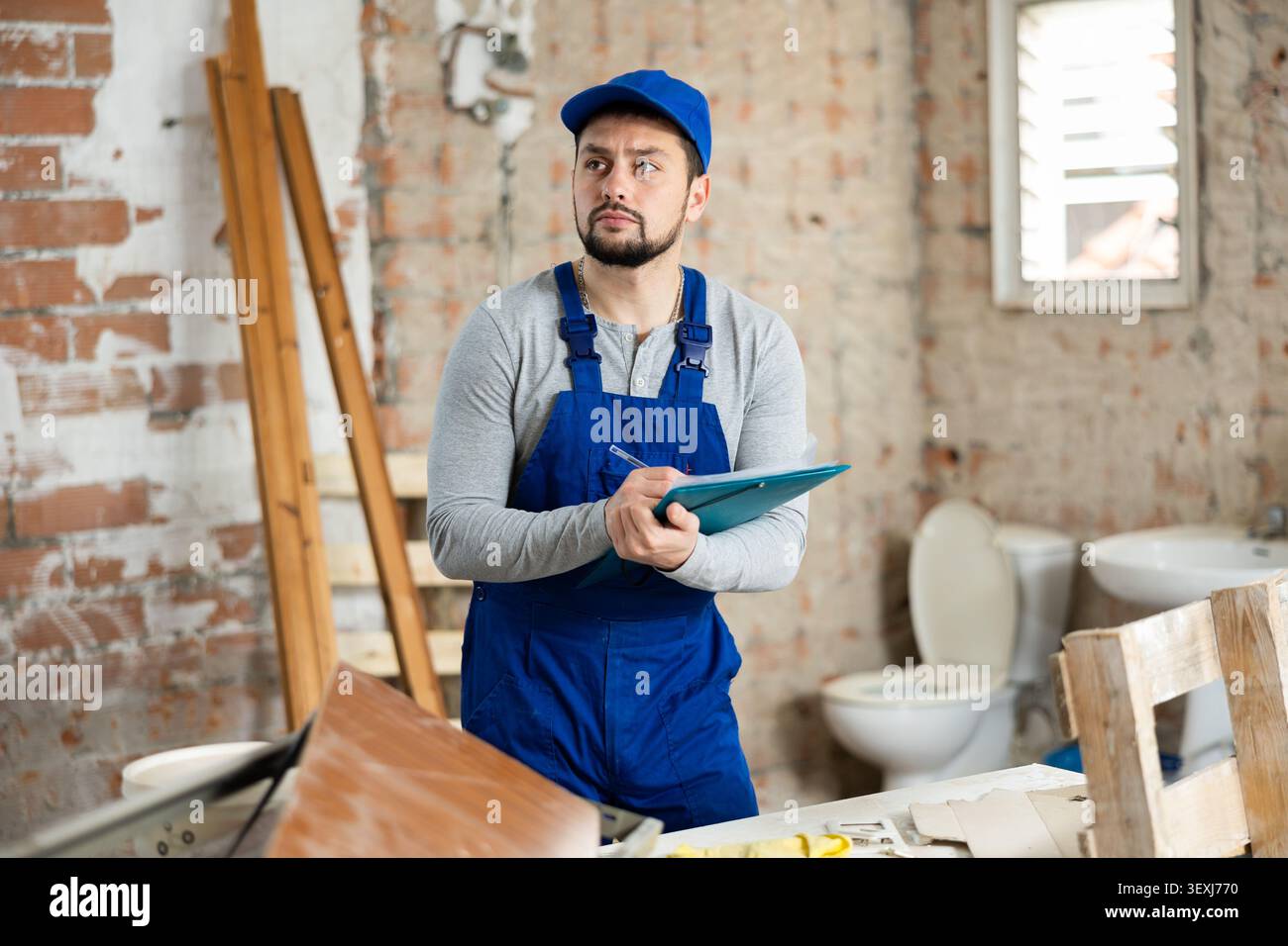 Focused contractor inspecting rooms and taking notes during renovation Stock Photo