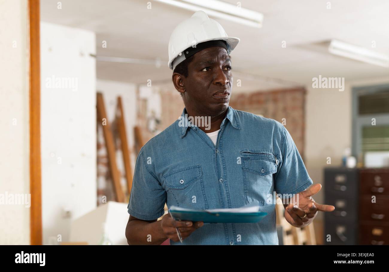 Strict building inspector standing with papers at construction site Stock Photo
