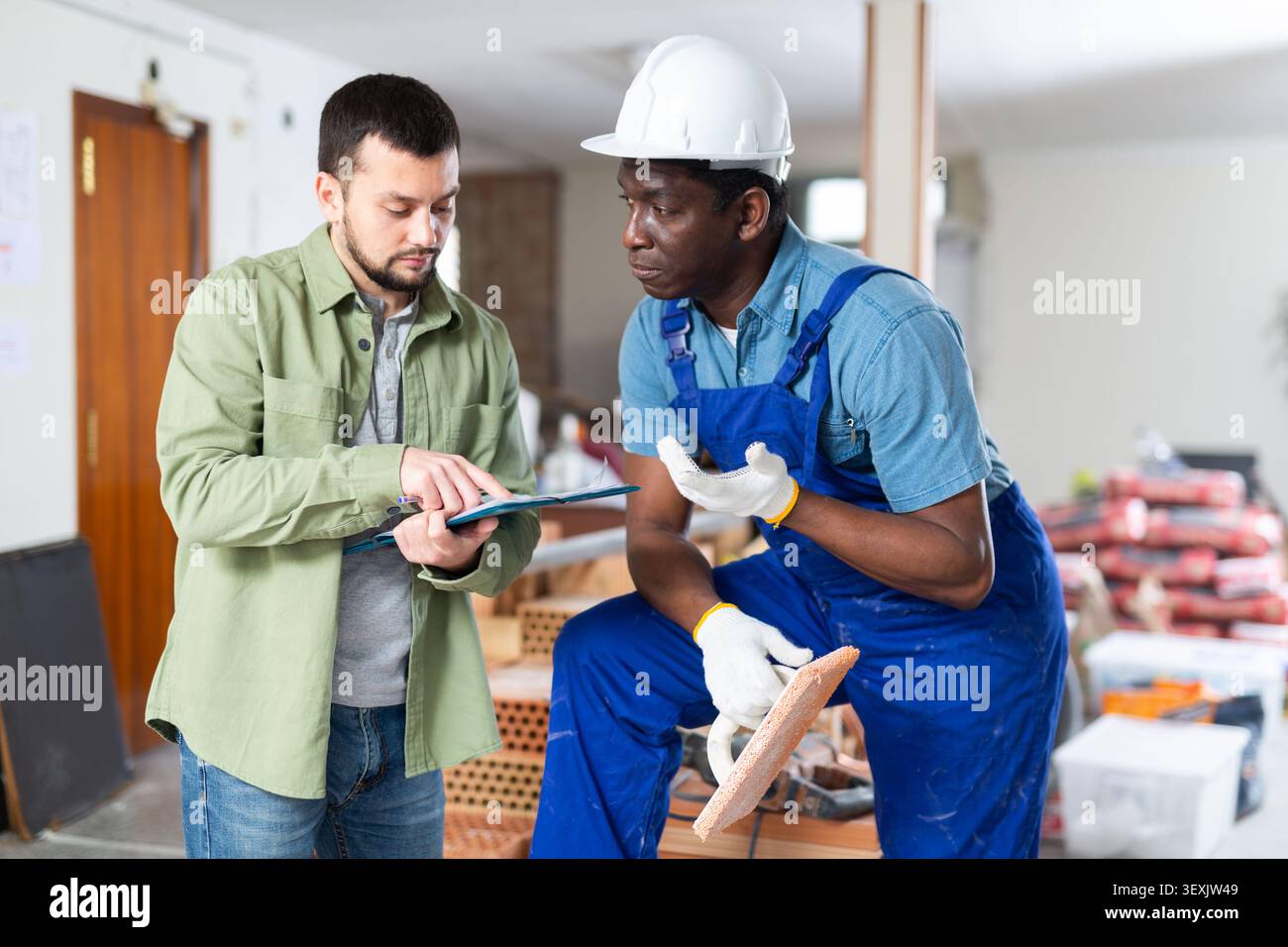 Engineer shows the estimate to a builder, explaining the working moments Stock Photo
