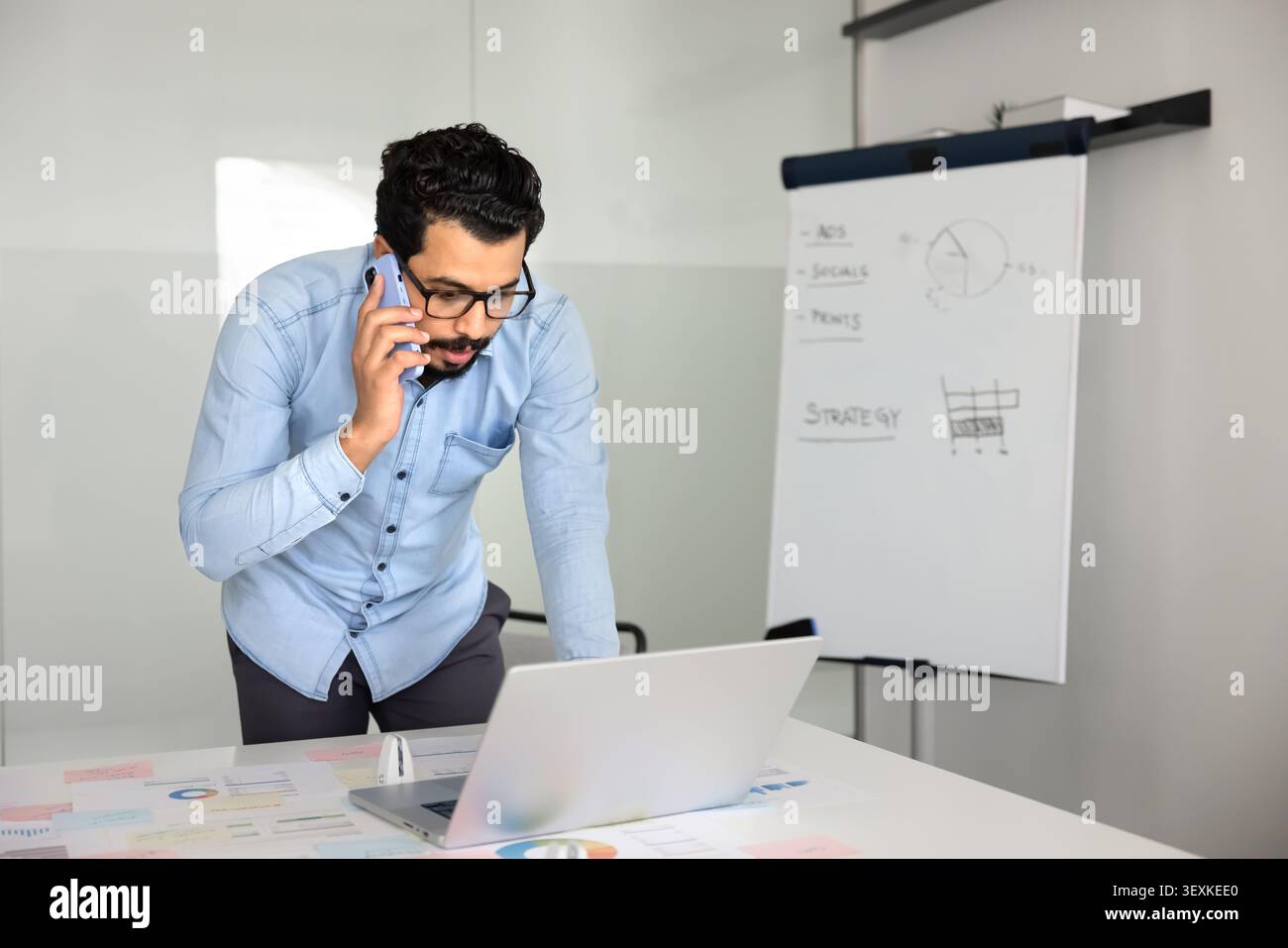 Middle Eastern businessman talking on phone while working on laptop Stock Photo