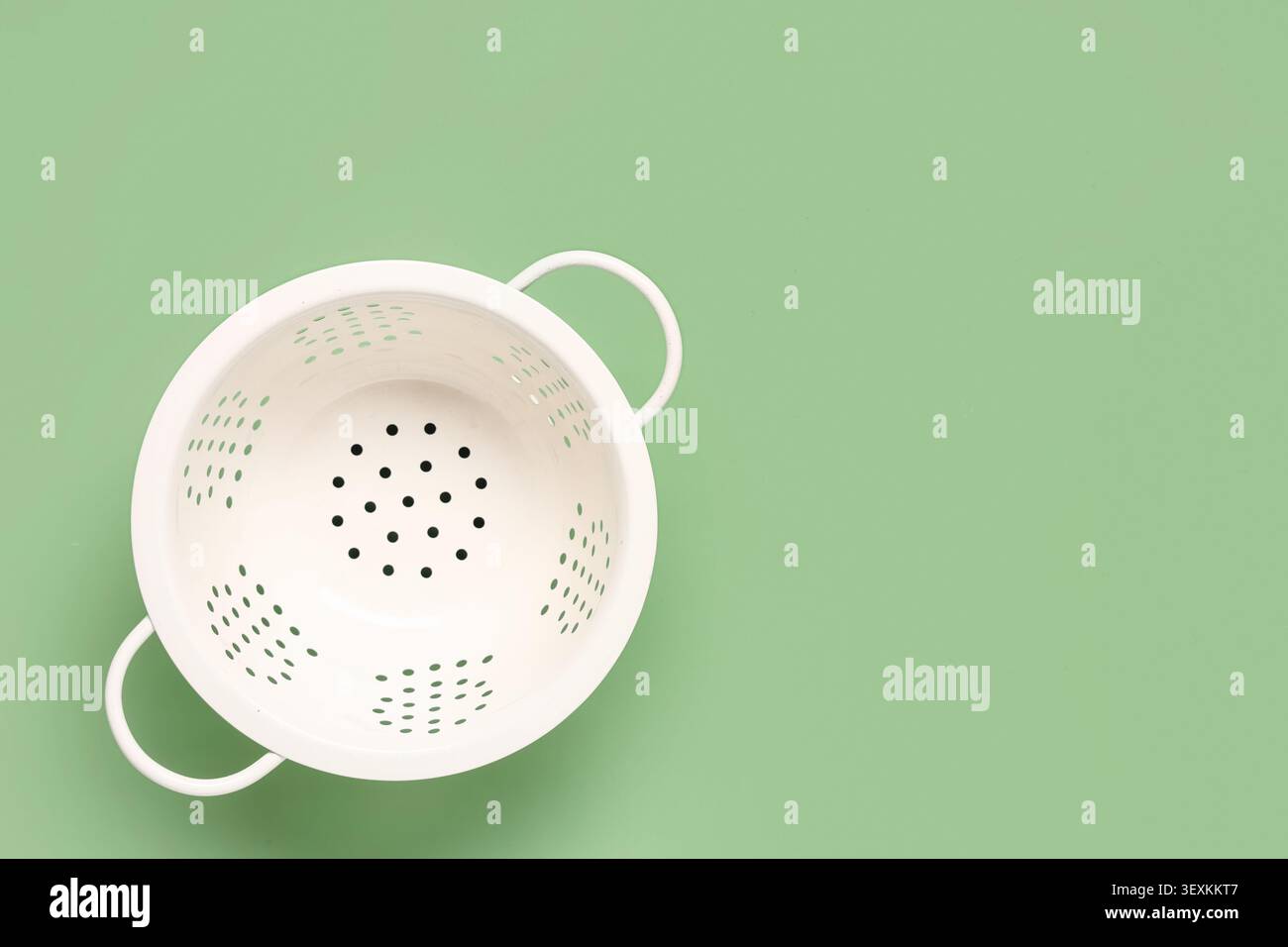 White colander on green background Stock Photo