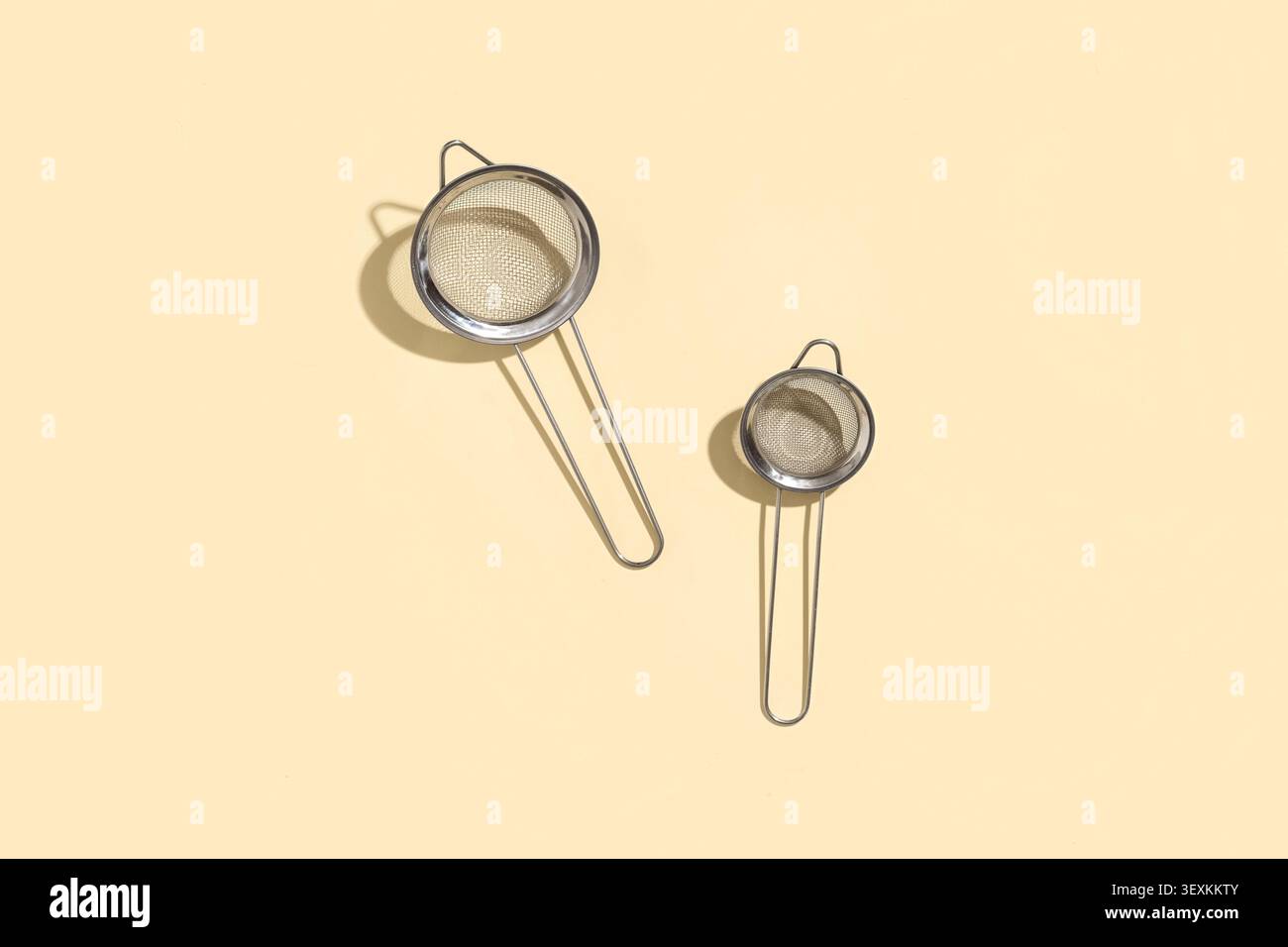 Two stainless steel tea strainers on beige background Stock Photo