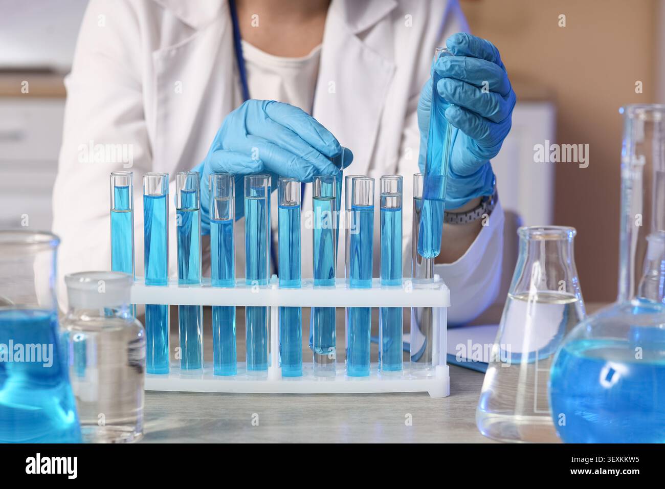 Scientist handling blue liquid in test tubes in laboratory Stock Photo