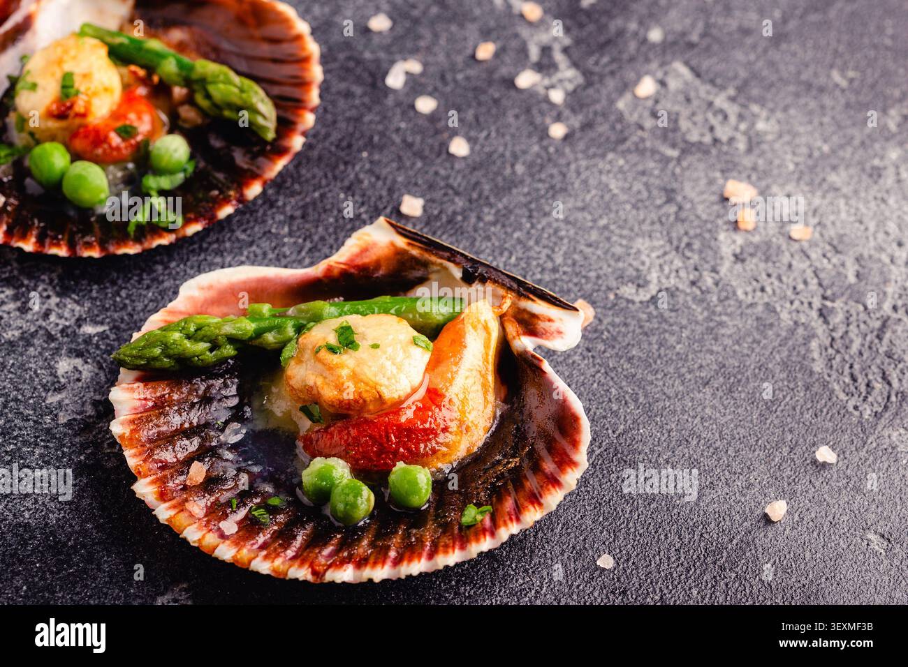 Cooked scallops with vegetables on a dark background Stock Photo