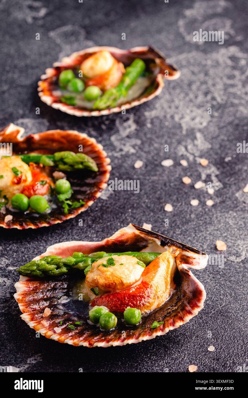 Cooked scallops with vegetables on a dark background Stock Photo